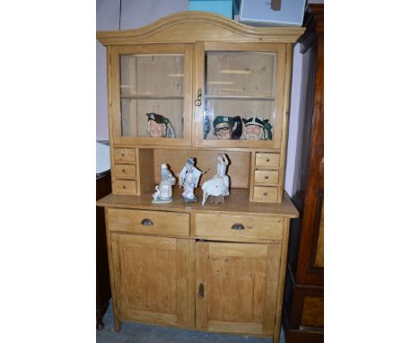 A 20th Century stripped pine kitchen dresser, the serpentine top above glazed panelled doors enclosing a shelf above three sh