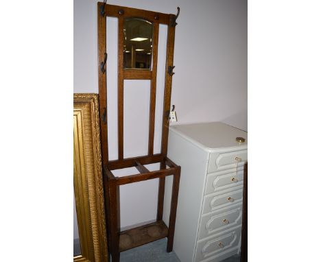 An early 20th Century hat and coat stand, the bevelled arched mirror panel flanked by six hanging hooks above stick receiver.