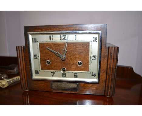 An Art Deco oak case mantel clock, the arabic dial above presentation plaque.