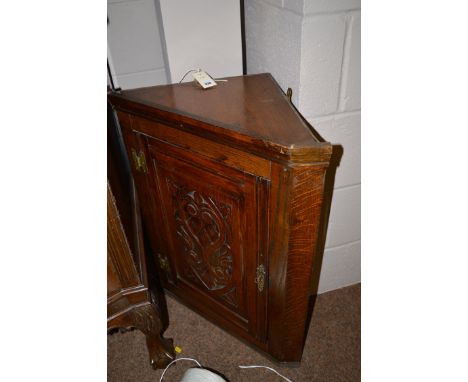 A late 19th Century carved and stained oak wall hanging corner cupboard with ornately carved panel door enclosing shelves.