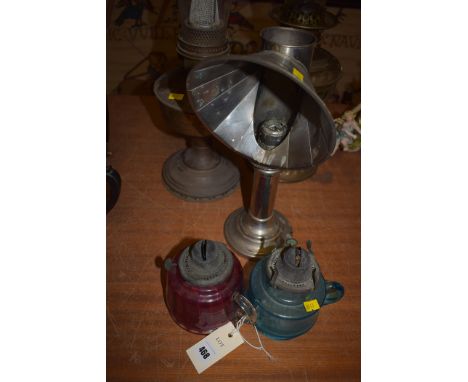 Two oil lamps; two coloured glass oil lamps; together with a chromed metal candle stick with reflector.  (5)