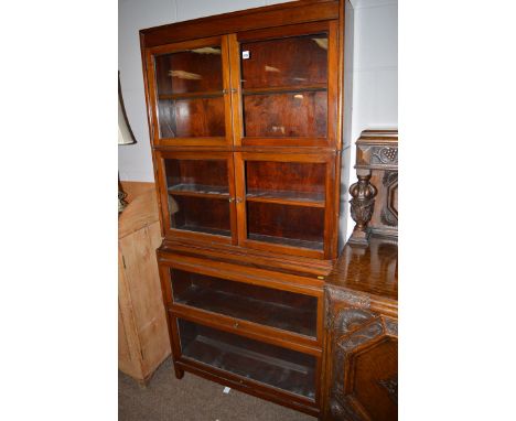 An early 20th Century sectional bookcase of four sections the bottom two with up and over glazed panel doors the top two with