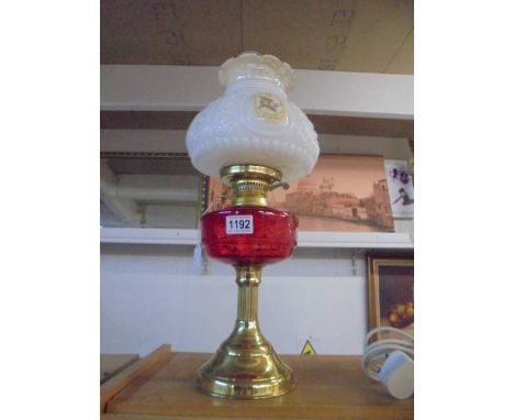 An oil lamp on a brass base with a red glass shade and floral shade. COLLECT ONLY.No damage of any sorts. Not currently worki