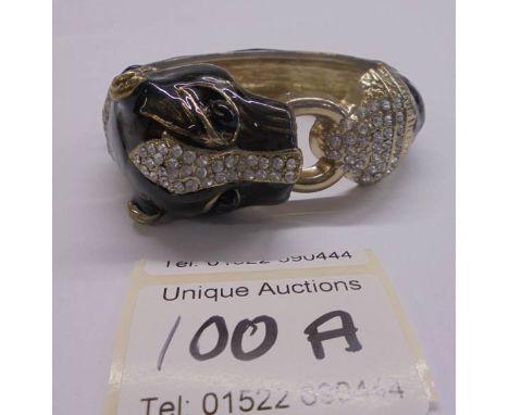 A paste and black metal coloured bangle in the shape of a leopard.