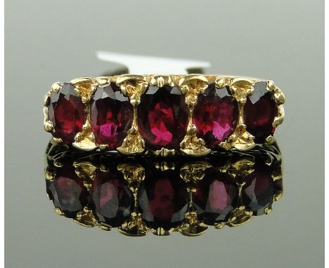 An 18ct gold five stone ruby ring,
with carved settings, setting width 20mm, size O.