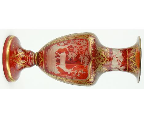 A Bohemian ruby glass vase
with engraved deer in a forest panels 13".
