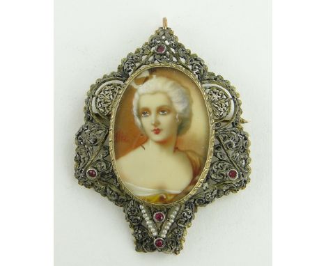 An ornate unmarked gold mounted pendant/brooch,
with inset painted portrait of a lady, in red stone and seed pearl set frame,