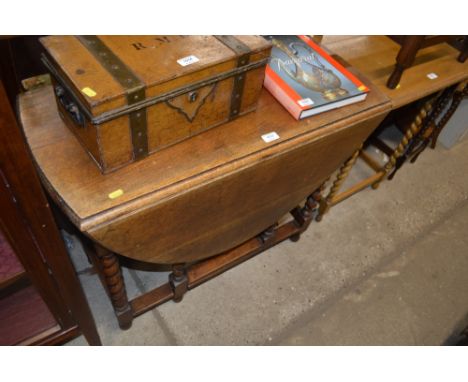 An oak gate leg table raised on barleytwist supports