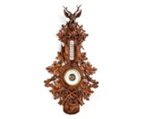 A late 19th century Black Forest carved wood wall barometer and thermometer, decorated a stag's head, oak leaves, acorns, dea