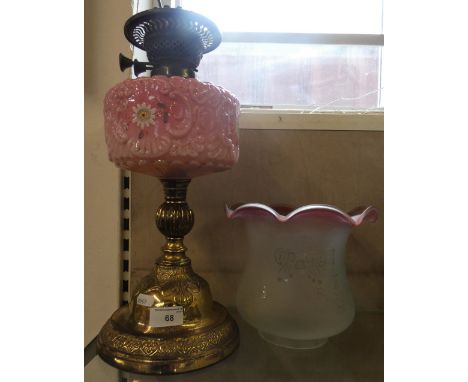 A brass oil lamp with pink glass bowl and etched glass shade