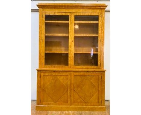 A karelian satin birch veneered bookcase on cupboard, with caddy top, twin glazed doors enclosing three pitch pine and veneer