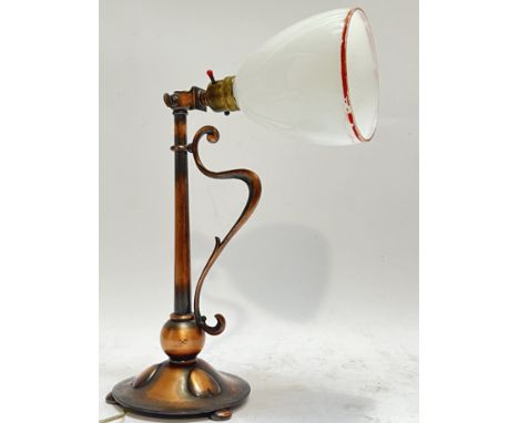 An Art Nouveau/Arts and Crafts style adjustable table lamp with copper-tone cast metal base embellished with heart-shaped mot