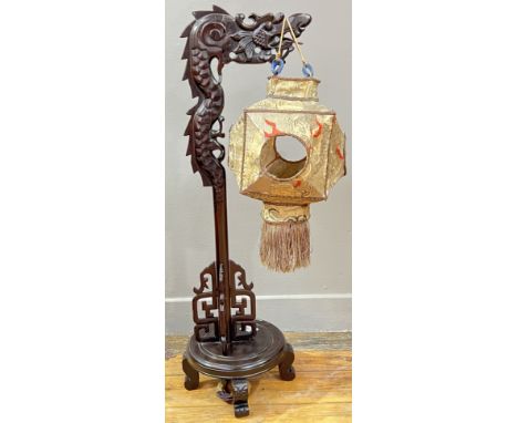 A Chinese stained and carved cherry wood lamp base in the form of a dragon raised on a circular base and four scroll supports