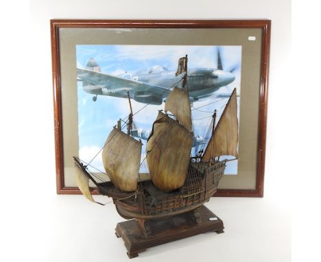 A wooden model of a ship, 57cm long, together with a print of a spitfire
