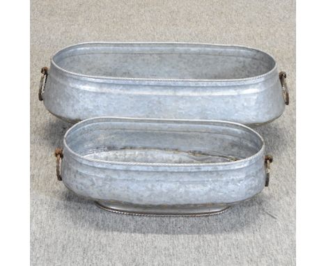 A galvanised oval metal planter, 70cm, together with another smaller