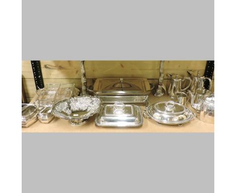 A shelf of silver plated items, to include a serving dish and cover, entree dishes, a pair of candlesticks and a basket