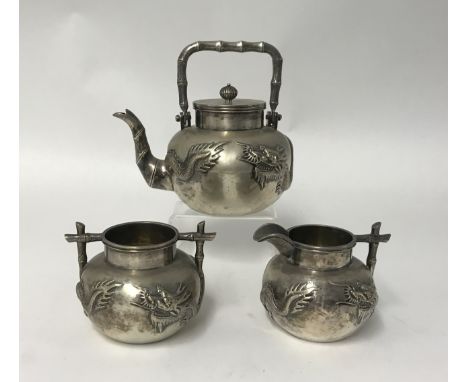 Chinese Export Silver, a three piece tea service comprising teapot, sugar bowl and cream jug, each decorated with embossed dr