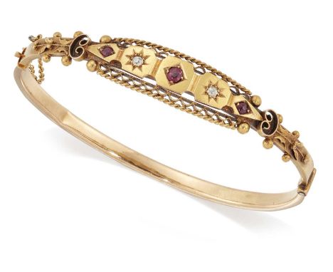 AN EDWARDIAN 15 CARAT GOLD RUBY AND DIAMOND HINGE OPENING BANGLE three graduated cushion-cut rubies spaced by old-cut diamond
