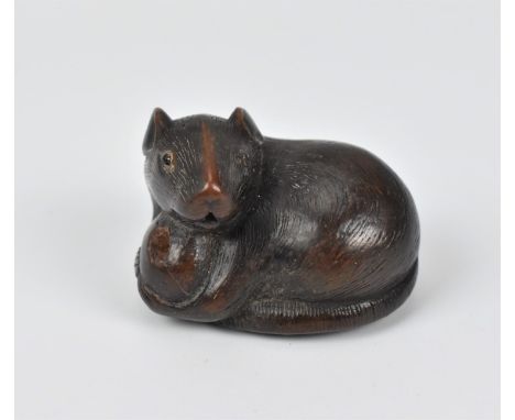 A Japanese carved wood netsuke, 19th century, modelled as a rat holding a nut, its tail coiled beneath him, with fine hair te