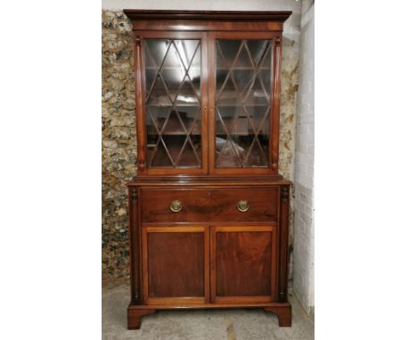 A Regency mahogany bureau bookcase, with moulded cornice above two astragal glazed doors enclosing three shelves, the lower p