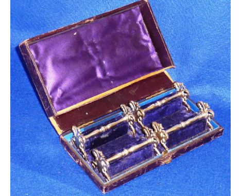 A set of four cased 19th Century heavy hallmarked silver Knife Rests, the pierced scrolling ends supporting the baluster shap