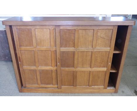 A Thompson of Kilburn "Mouseman" adzed oak Bookcase fitted with adjustable shelves and enclosed by a pair of sliding panelled