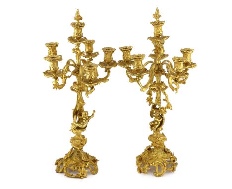A pair of Victorian style ormolu six light candelabra with rococo scroll extinguishers, scrolling branches and floral applied