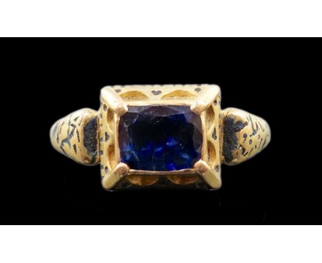 An antique high carat gold, black enamel and collet set cushion cut sapphire set 'poison' ring, the stone set in a raised cen