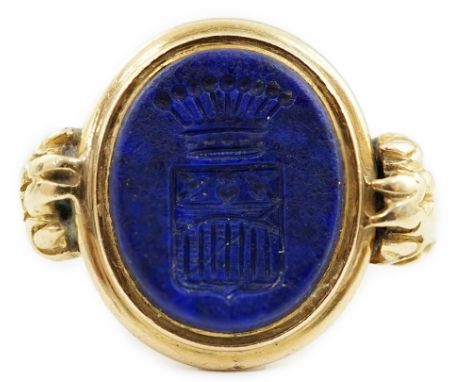 A 19th century gold and lapis lazuli set intaglio ring, with lion's paw shoulders and matrix carved with family crest below a