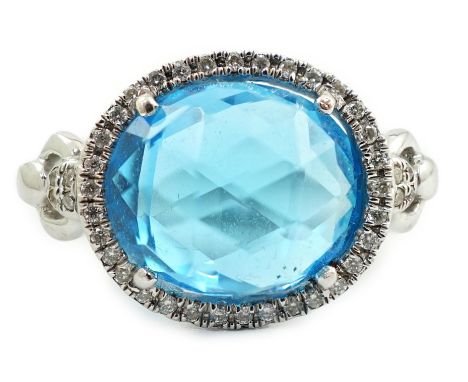 A modern 18ct white gold and facetted oval cut blue topaz set dress ring, with diamond chip set border and shoulders, size L,