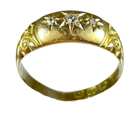 An Edwardian 18ct diamond set three stone ring. Set with three small diamonds, with scroll engraved shoulders, Birmingham hal