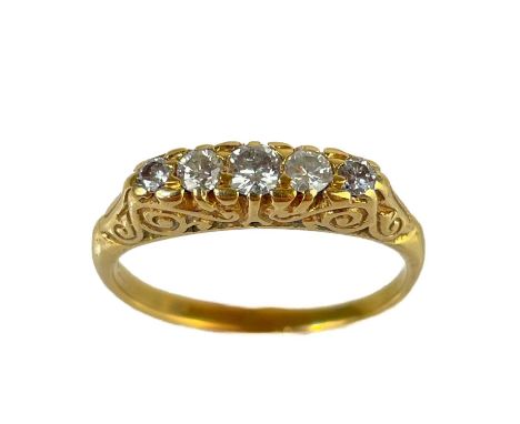 An Edwardian gold diamond set five stone ring.  The central diamond measures 0.07ct, the diamonds in a foliate scroll setting