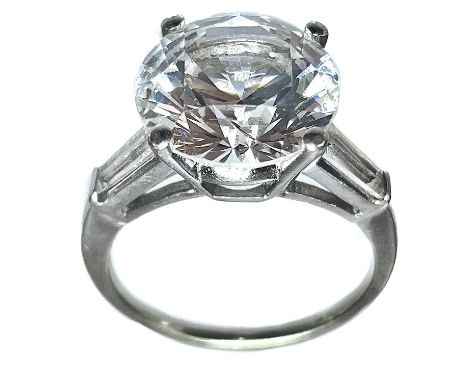 A 9ct white gold white stone set solitaire ring. The large white stone measuring 6ct, the shoulders with tapered baguette sto