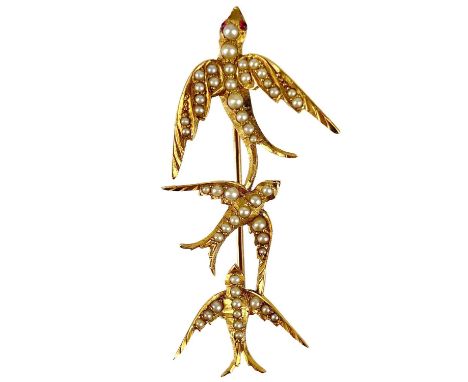 An Edwardian high purity gold (tests 14ct) pearl and ruby set bird brooch. Modelled as three swallows, one set with small rub