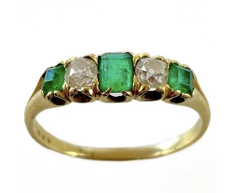 A high purity gold (tests 18ct) emerald and diamond five stone ring. The central emerald measuring 0.15ct approximately, tota