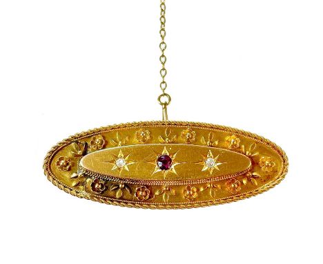 A Victorian 15ct diamond and ruby three stone brooch. Of oval form with two diamonds measuring 0.02ct, width 43mm, 5.17g.