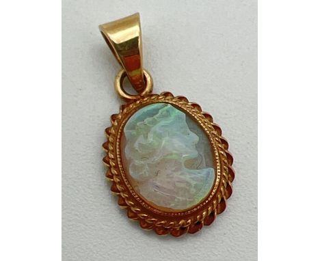 A 9ct gold cameo style carved opal pendant. Oval pendant with rope design to edge of mount. Classic design carved profile of 