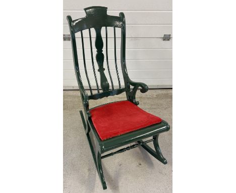 A vintage painted wood rocking chair with spindle back and turned detail. Painted dark green with red velvet upholstered seat