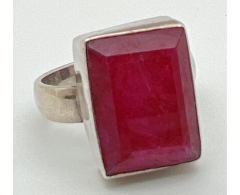 A modern silver dress ring set with a rectangular cut ruby. Inside of band marked 925. Ring size N. Stone approx. 1.5 x 1cm. 