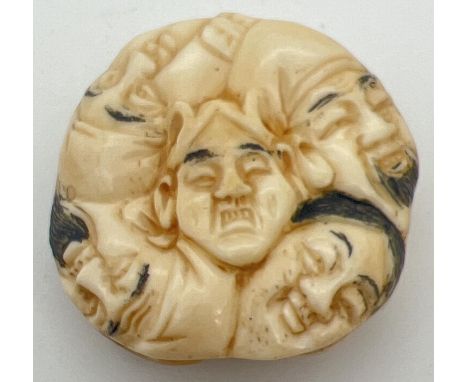 A carved Chinese circular shaped netsuke depicting many faces to both sides. With signature mark. Approx. 4.25cm diameter. 