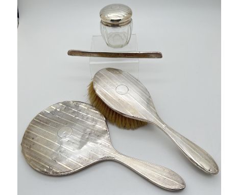 An Art Deco silver dressing table/vanity set with stylised engine turned decoration. Circular empty cartouche to hand mirror,