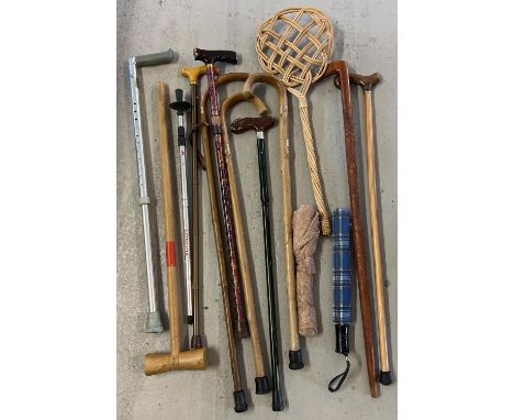 10 walking sticks in various materials, lengths and designs to include carved wood. Together with 2 umbrellas, a carpet beate