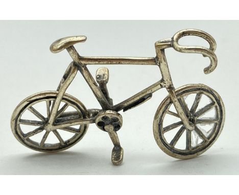 A Continental silver miniature model of a bicycle, with moving wheels. Stamped 800 to underside. Approx. 3cm x 4.5cm and weig