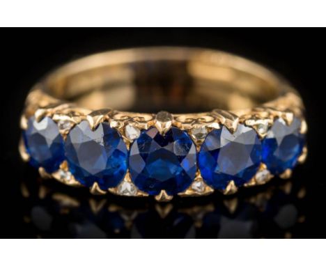 A late 19th century gold and sapphire five-stone, half-hoop ring: with cushion-shaped blue sapphires graduated from 5mm long 