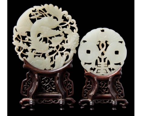 Two Chinese carved and pierced celadon jade discs: the larger in the form of a phoenix amongst peonies and foliage, 20th cent
