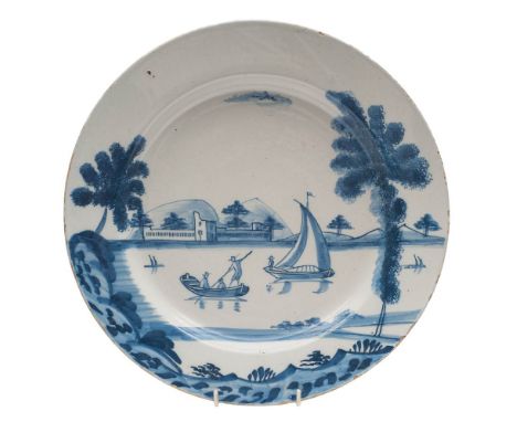 A Bristol blue and white delftware dish: painted with a coastal landscape with buildings, boats, figures and sponged trees, c
