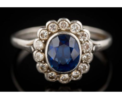 A sapphire and diamond oval cluster ring: the oval sapphire approximately 7.5mm long x 6.5mm wide x 3.8mm deep, within a surr