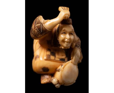 A Japanese carved ivory netsuke depicting a musician: beating a drum with his fan, signed Sugi Yoshi, 4.5cm high, Meiji perio