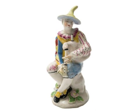 A Bow figure of Harlequin playing the bagpipes: after the Meissen original, the seated figure wearing a striped and chequered