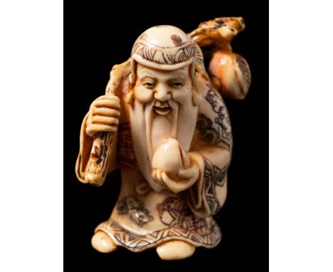 A Japanese carved ivory and stained netsuke depicting a Sennin: in traditional costume holding a gourd in one hand and a stic